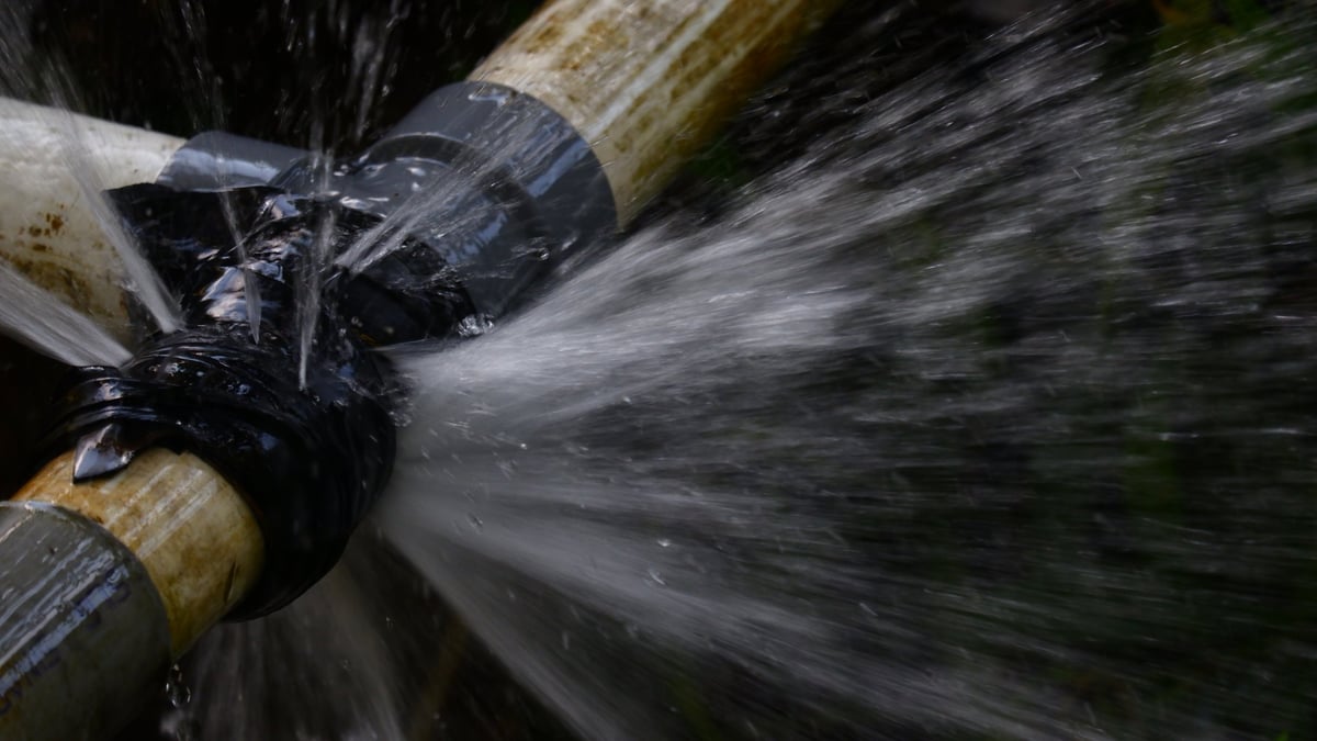 Water spraying out of a leaking copper pipe showing the pressure caused by a burst pipe in a UK home